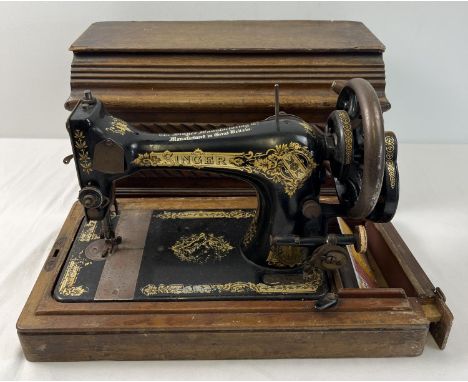 A vintage Singer hand crank sewing machine, in wooden case. Painted black with gilt floral decoration and name to machine. Gr