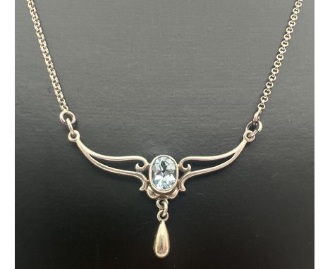 An Art Nouveau design silver fixed pendant necklace set with an oval cut blue topaz and a small silver drop. Belcher chain wi