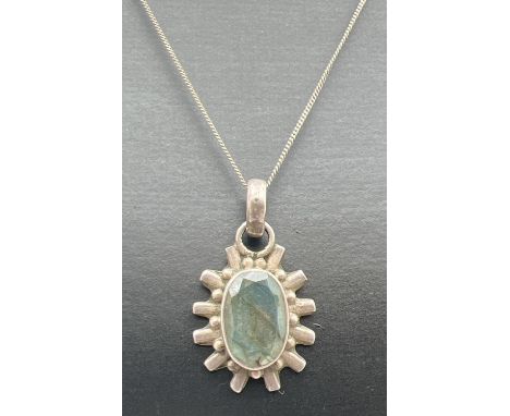 A silver sun-ray design oval shaped pendant set with labradorite, on a 16" fine curb chain with spring ring clasp. Silver mar