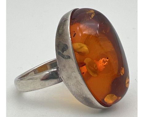 A large silver dress ring set with an oval cut amber cabochon. Ring size S. Silver mark to inside of band. Cabochon approx. 2