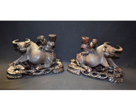 A pair of late 19th century Chinese hardwood carvings, of a boy astride a water buffalo, the boy carrying a haystack on his o