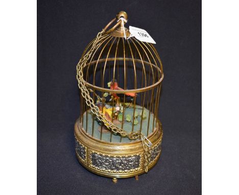 A brass and silvered singing bird automaton, the domed cage with two brightly feathered occupants, above a bas relief frieze,