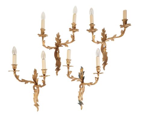 A SET OF FOUR GILT METAL TWIN LIGHT WALLL APPLIQUES, IN LOUIS XV TASTE, 20th century, cast opposing as two pairs, the electri