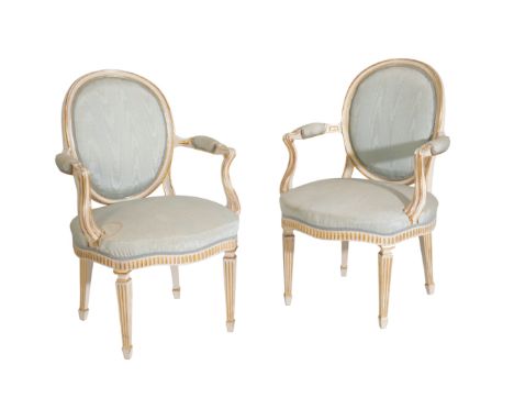 A PAIR OF CARVED, PAINTED AND PARCEL GILT FAUTEUILS IN LOUIS XVI STYLE, early 20th century, the light blue upholstered oval b