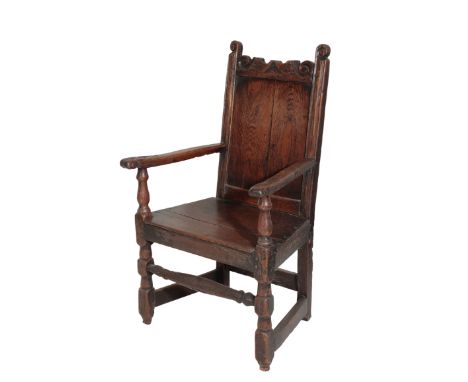 AN OAK WAINSCOT CHAIR, 17th century, the panel backrest toprail carved with scrolling foliage between twin scrolled finials, 