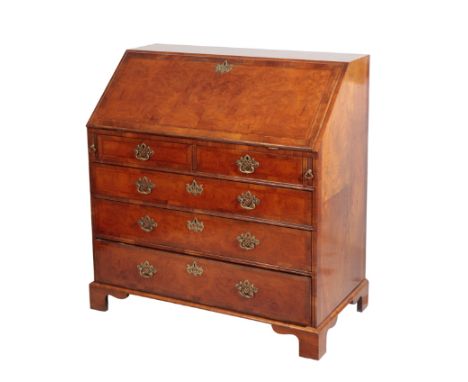 A WALNUT AND FEATHER BANDED BUREAU IN GEORGE II STYLE, the fall front opening to a fully fitted interior of drawers and pigeo