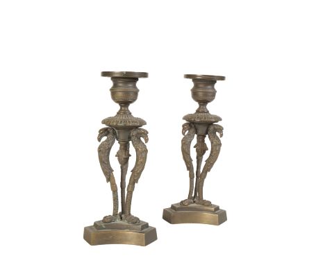 A PAIR OF REGENCY BRONZE CANDLESTICKS on three monopodia supports with eagles-head terminals and triform bases, 17.5cm high, 