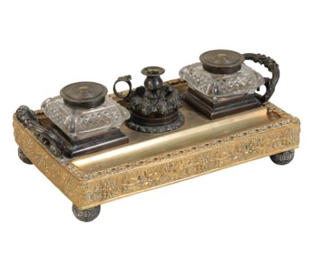 A GEORGE IV PATINATED AND GILT BRONZE STANDISH, circa 1825, of rectangular form, with twin hobnail cut glass ink wells flanki