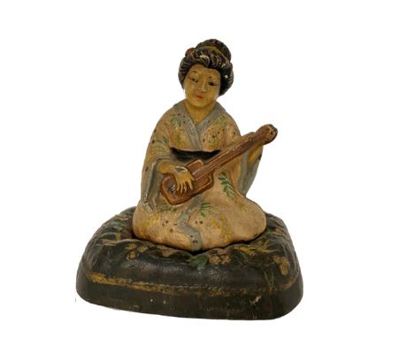A HUBLEY CAST IRON DOORSTOP IN THE FORM OF A GEISHA modelled seated on a cushion playing the shamisen, retaining the apparent