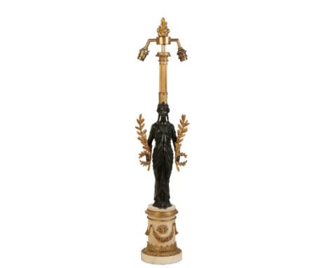 A PATINATED AND GILT BRONZE TWIN LIGHT TABLE LAMP, IN EMPIRE TASTE, the electrical fitments with flambeau finial, above a ree