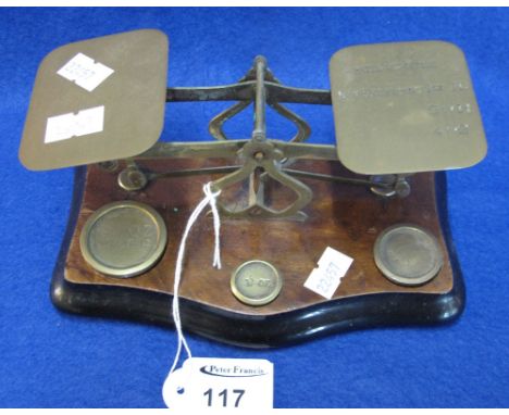 Set of brass postal scales on serpentine shaped wooden base with weights.