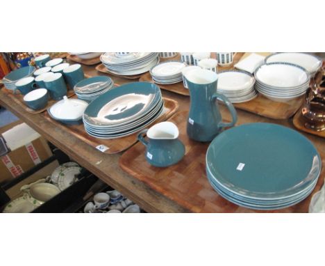 Three trays of Poole Pottery items on a turquoise ground to include: teacups and saucers; mugs; various plates; jugs etc. (3)