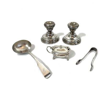 A selection of silver. To include a pair of weigthed squat candlesticks, Birmingham 1912, a George V mustard pot with blue gl