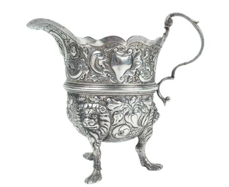 An mid-18th century Georgian Irish silver cream jug by William Walsh. Of helmet form embossed with shells, fruit and foliate 