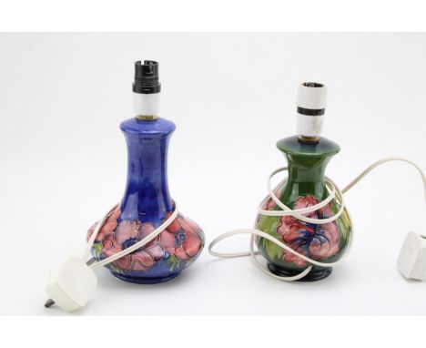 Two Moorcroft lamp bases to include a clematis on green lampbase and a similar on blue (2), 25cm tall.  In good condition wit