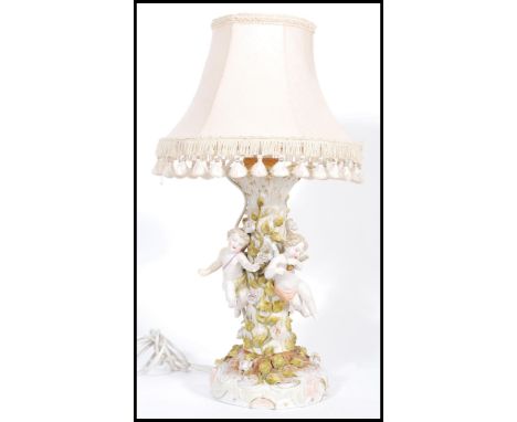 A Sitzendorf&nbsp;ceramic table lamp featuring three cherub figurines around a central naturalistic tree column. Decorated wi