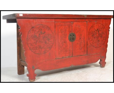 A Chinese 19th / 20th century large red lacquer sideboard of shaped form. The worn flared top over cupboards depicting mythic