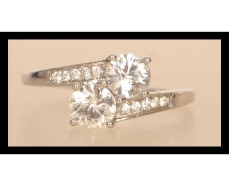 A hallmarked 9ct white gold crossover ring having two large brilliant cut white stones with white stone set shoulders. Weighs