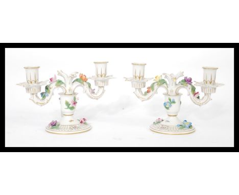 A pair of Dresden porcelain double sconce candelabras, each decorated with applied ceramic flowers and gilt motifs and raised