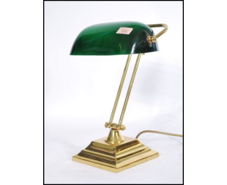 A vintage 20th century bankers desk lamp having an adjustable green glass shade raised on a brass support and good brass base