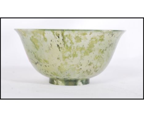 A Chinese jade tea / finger bowl / libation cup of typical form having a mottled and clear colouring. Raised on a small circu