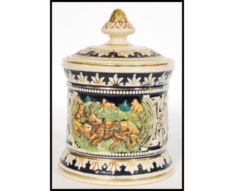A vintage 20th century German stoneware tobacco jar humidor pot having relief scenes of lions and lionesses hunting an ibex. 