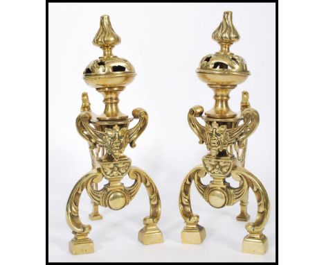 A pair of 19th century cast brass fireside dogs raised on block feet with scrolled legs. Grotesque masks to front with lamp a