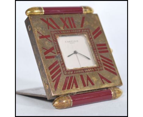 A vintage 20th century Cartier Paris travel desk clock having white enamel signed face with brass chapter ring and red Roman 