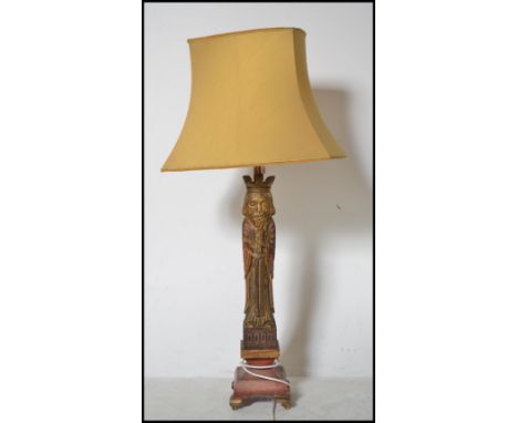 A vintage medieval style carved wooden table lamp of tall form depicting a king raised on plinth base.