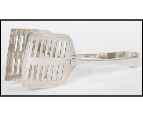 A large pair of early 20th century Edwardian serving tongs having a shaped open cut end with non silver joining rod. Hallmark