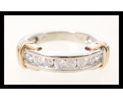 A stamped 10k white gold ring having 8 channel set brilliant cut diamonds, and yellow gold detailing. Size L.