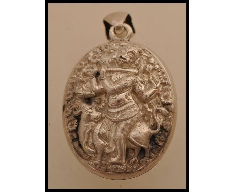 A large Indian silver white metal pendant locket featuring&nbsp;Kokopelli and Indian fertility God playing a flute with a cow