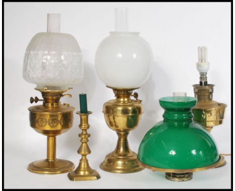 A collection of three brass oil lamps dating to the early 20th Century, each lamp raised on a pedestal base with fitted glass