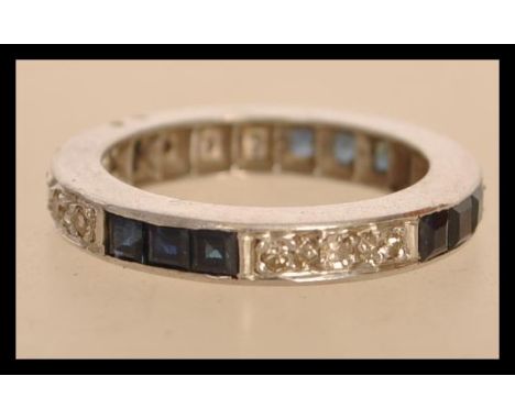 A white gold eternity ring set with square blue sapphires and round cut diamonds. Size K.5. Weight 5.0g.