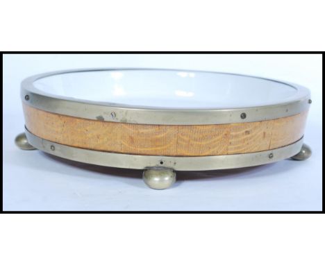 An early 20th century coopered oak barrel style wooden bound dog bowl, the wood secured with brass hoops and raised on round 
