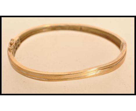 A yellow metal but tests as 9ct gold bangle bracelet having a hidden clasp AF with fold over latch. Weighs 14.3 grams.