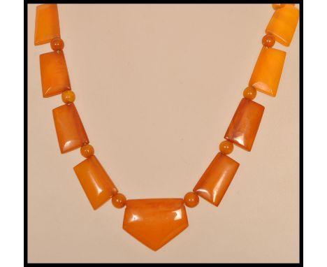 A vintage Art Deco amber bakelite necklace with yellow metal clasp. Large axe shaped panels with smaller bead spacers.