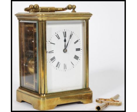 An early 20th century brass carriage clock having a white enamelled face and faceted hands, a swing handle to the top, expose
