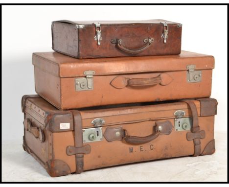 A stack of three vintage early 20th century graduating leather suit cases, each in brown leather with brass catches and lever