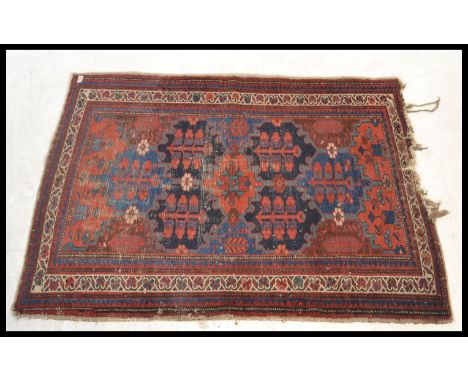A vintage 20th Century floor rug / mat on red ground, central panel with geometric borders with tasselled ends.&nbsp;Measures