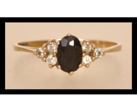 A hallmarked 9ct gold blue sapphire and white stone ring having a central faceted blue stone flanked by three white stones ei