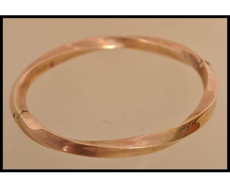 A 9ct gold bangle bracelet of twist form having a hidden clasp. Weighs 13 grams.