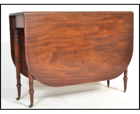 A good 19th century George III solid mahogany drop leaf / gateleg dining table being raised on ring turned, tapering legs wit