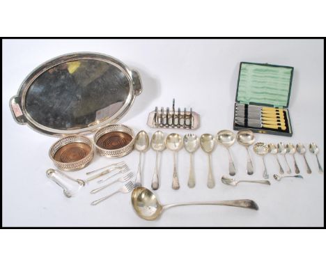 A collection of silver plated items to include a toast rack and tray, various ladles and serving spoons, sugar tongs, caddy s