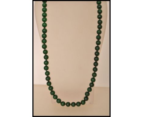 A Chinese deep green jade bead necklace consisting of over 60 circular jade beads.