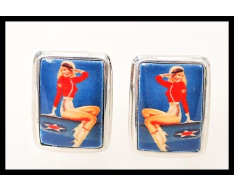 A pair of silver mens cufflinks having square enamel panels depicting the figure of a vintage pin up girl. Weight 12.6g.