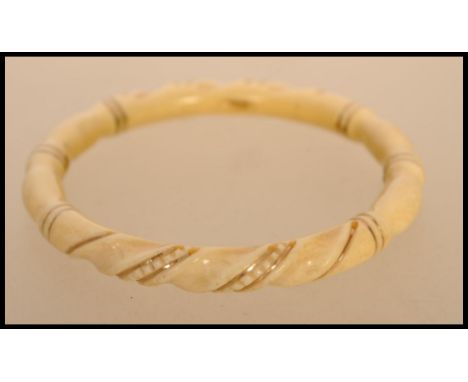 An early 20th century ivory and gold banded bangle. The carved bangle having twist design with gold bands.