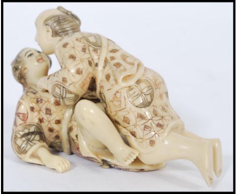 A pair of Japanese Karma Sutra erotic ivorine figures of a couple along with a pair of reclining ceramic Chinese figures. Tal