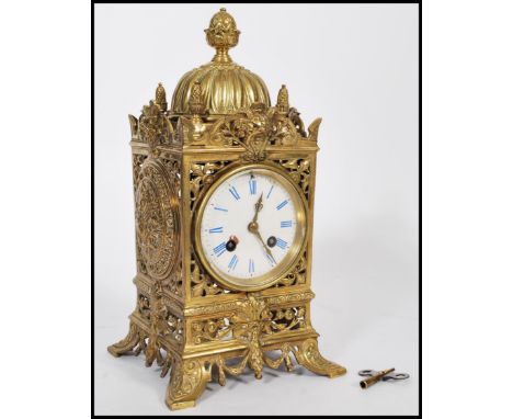 A 19th century French gilt brass mantel clock having grotesque face masks and pineapple finials. The white enamel face having