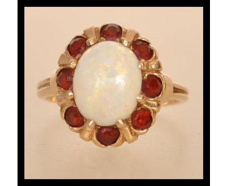 A marked 14ct gold opal cluster ring having a central opal panel with a halo of orange stones. Weighs 4.3 grams size M.